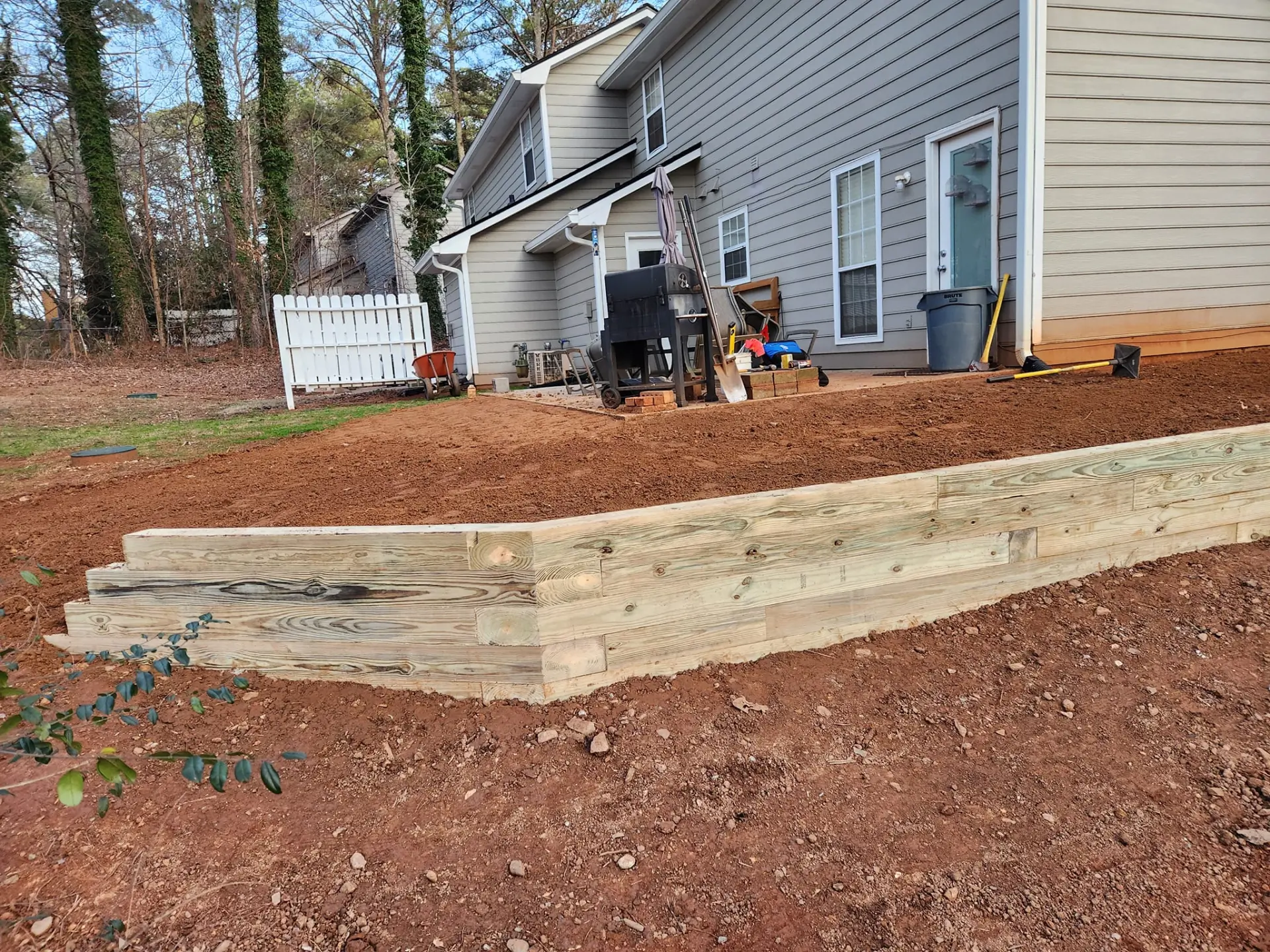 Completed timber retaining wall wrapping around a backyard slope